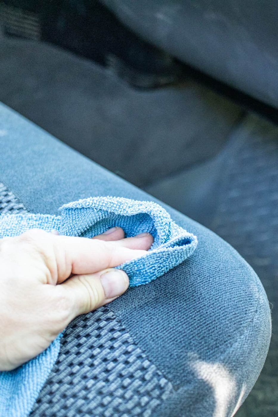 Wiping a car seat with a microfiber cloth.