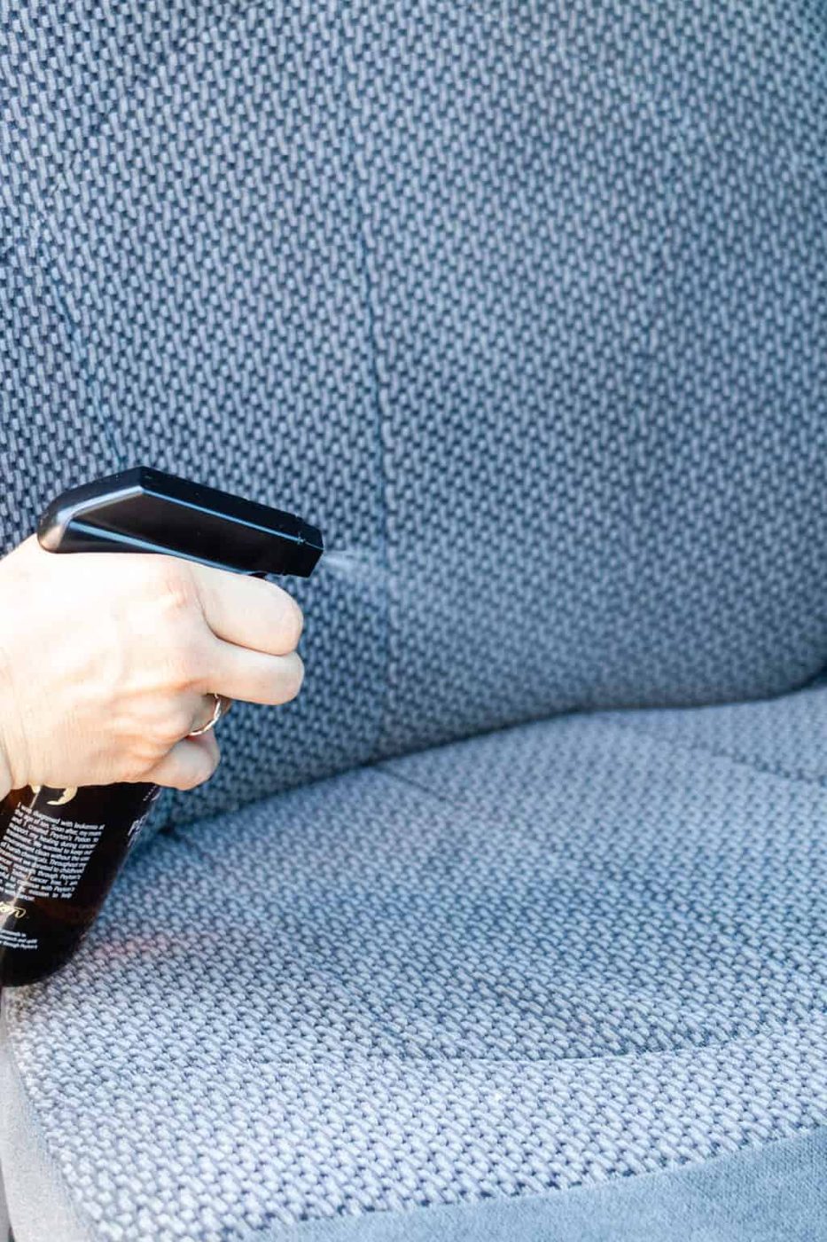 Spraying cleaner on a car seat.