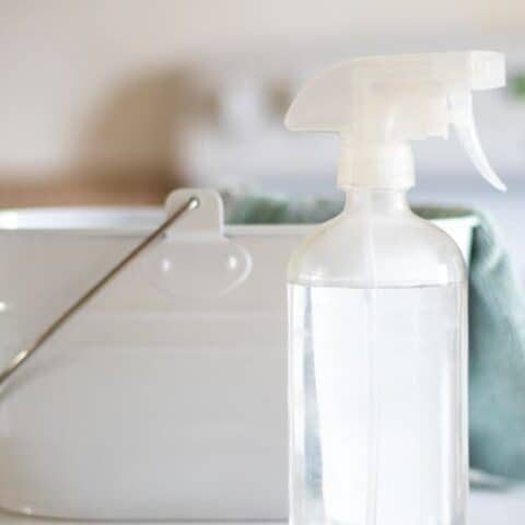 White cleaning caddy with non toxic spray bottle and blue cloth.