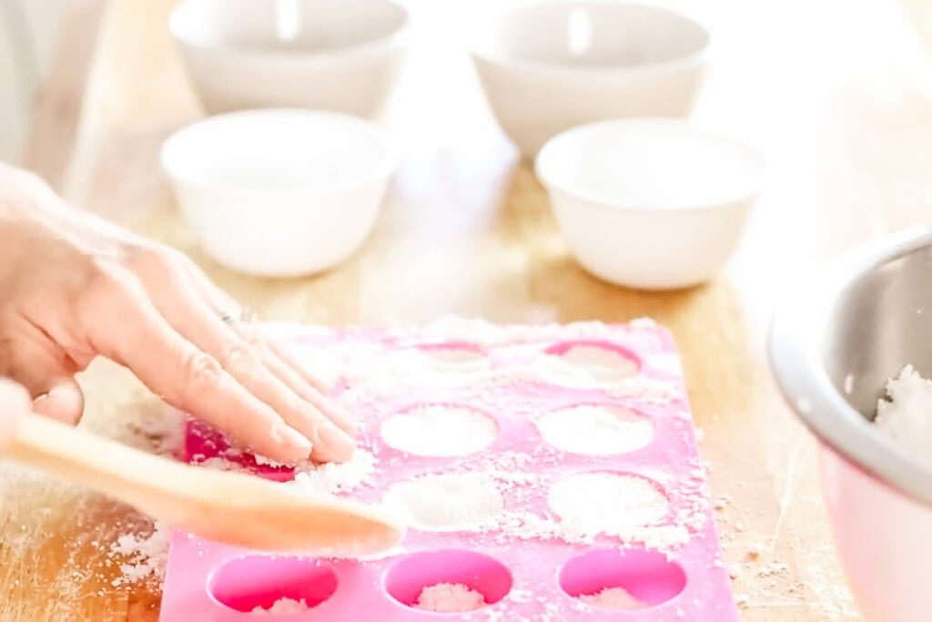 Pressing the dishwasher soap tabs into the silicone molds and packing tightly.