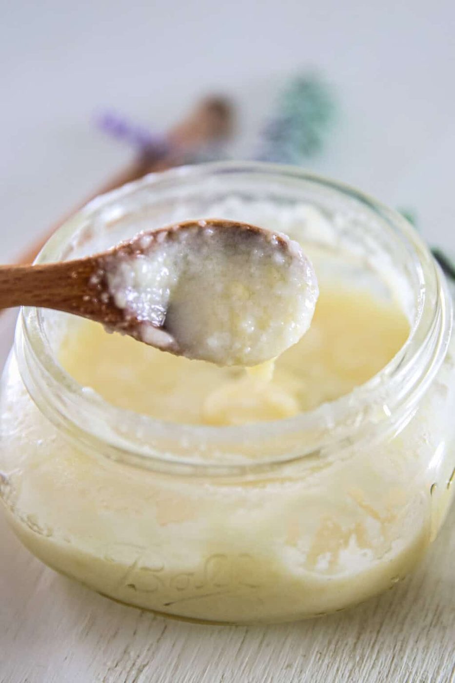 A spoonful of DIY face wash held over a jar of face wash.