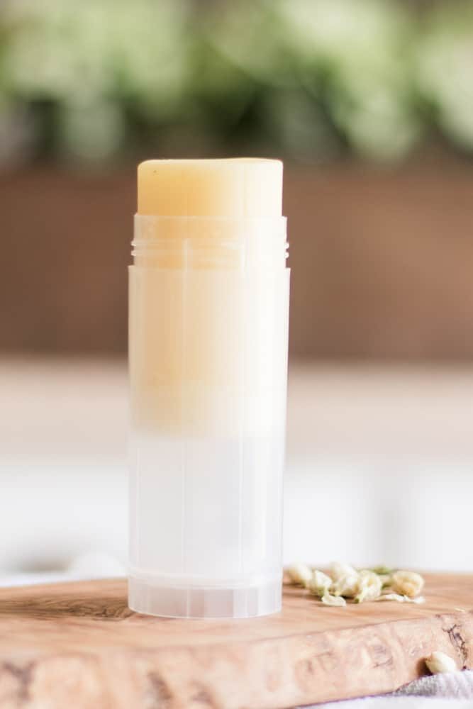 Homemade foot balm stick on wood cutting board.