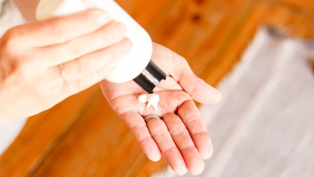 Squeezing the homemade foot lotion into our hands before applying it to our feet.