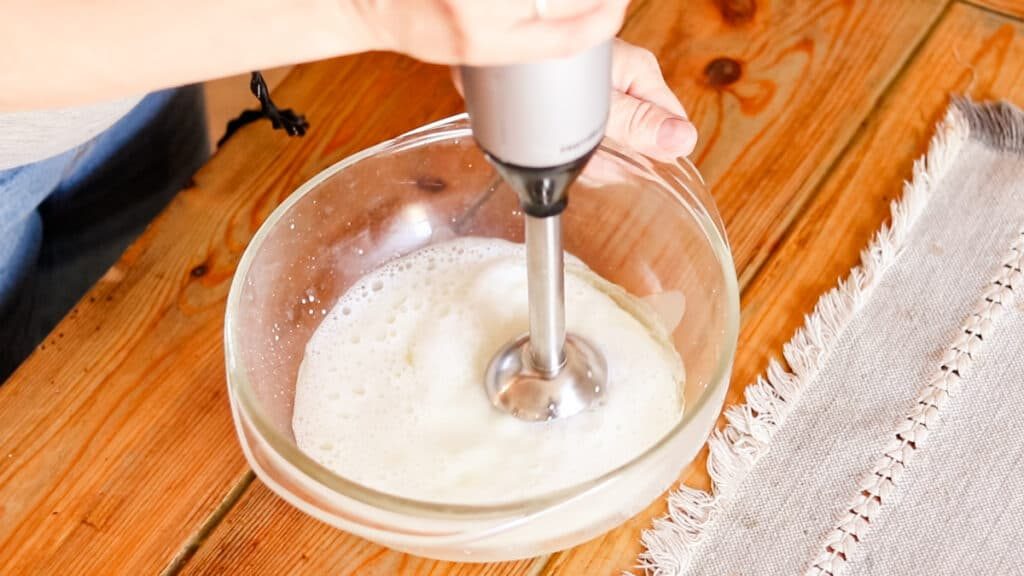 Mixing the lotion with an immersion blender to create an emulsion.