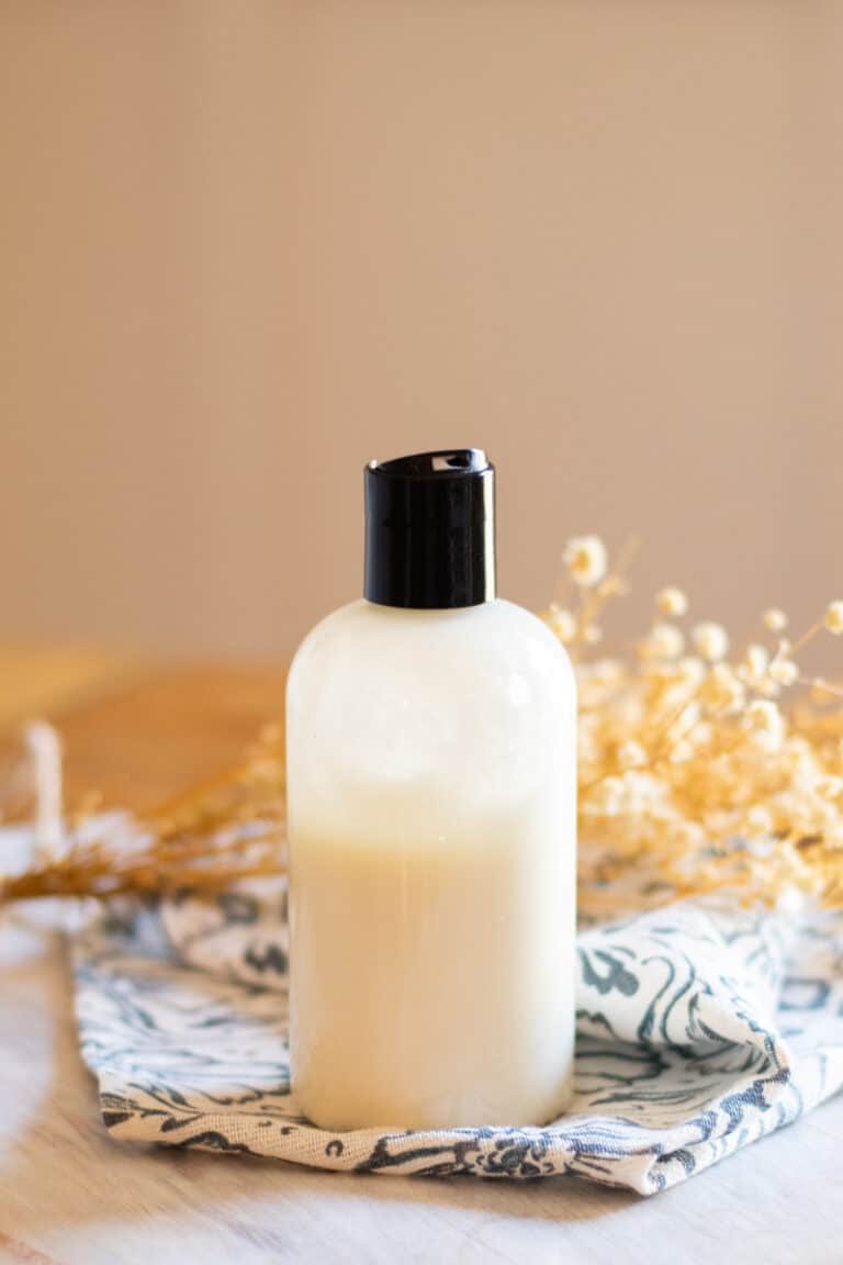 Squeeze top foot lotion with soothing ingredients on a wooden table with dried flowers in the background.