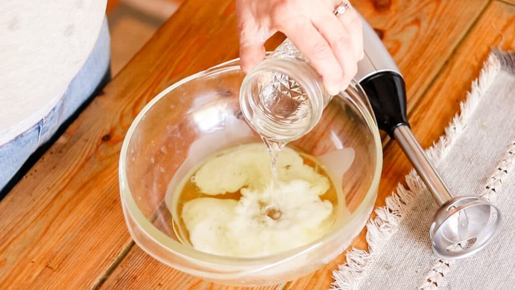 Pouring the distilled water into the bowl with the melted oils.