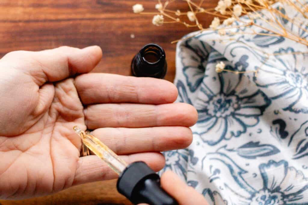 Homemade hair growth oil being dispensed into our hand before working it into the strands.