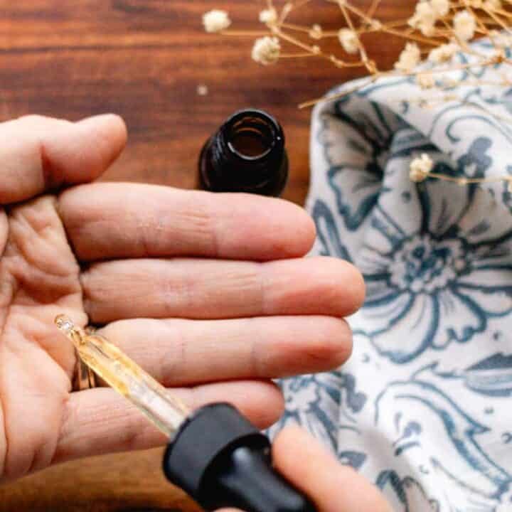 Homemade hair growth oil being dispensed into our hand before working it into the strands.