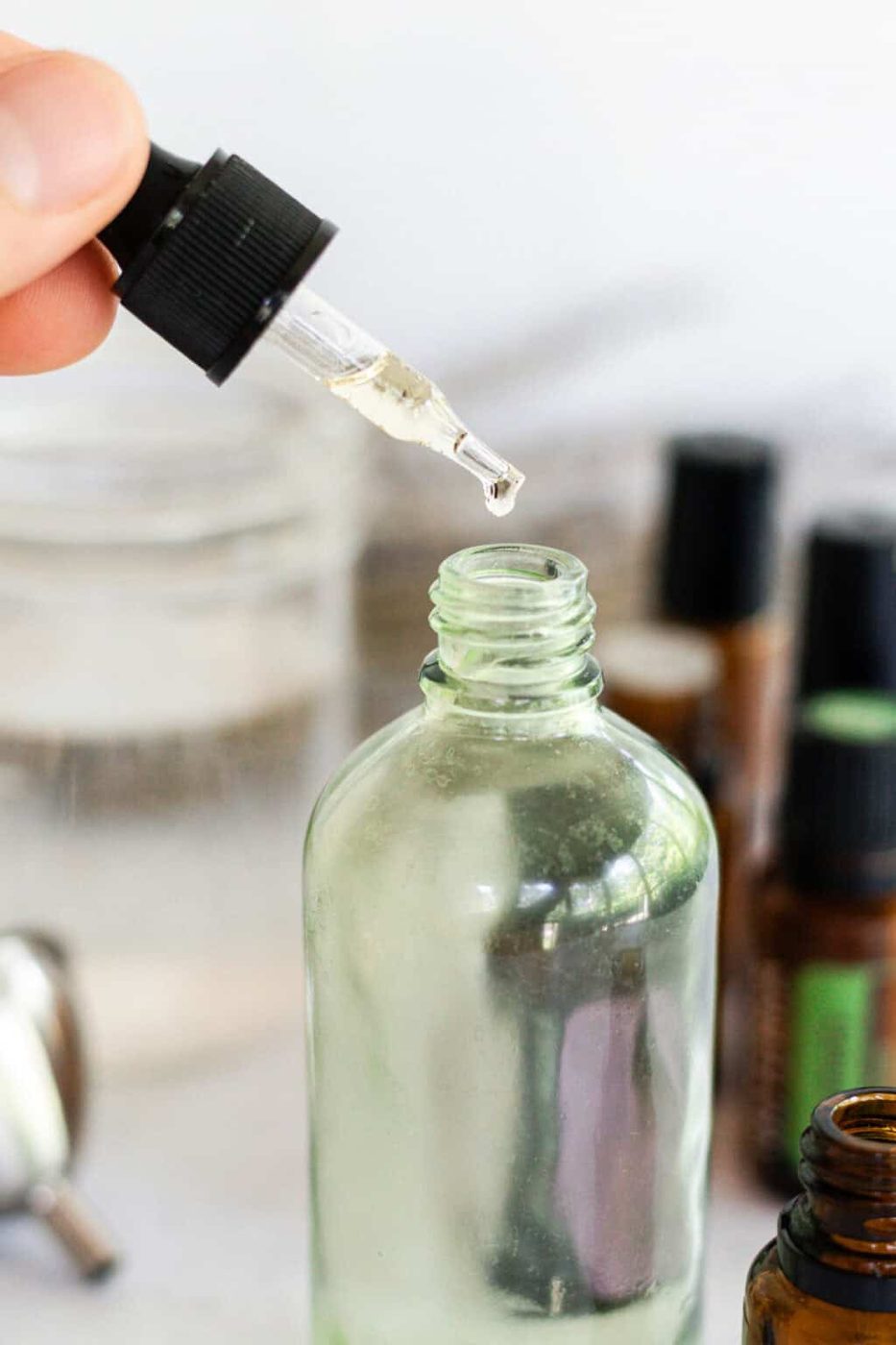 Adding essential oils to a glass spray bottle with a dropper.