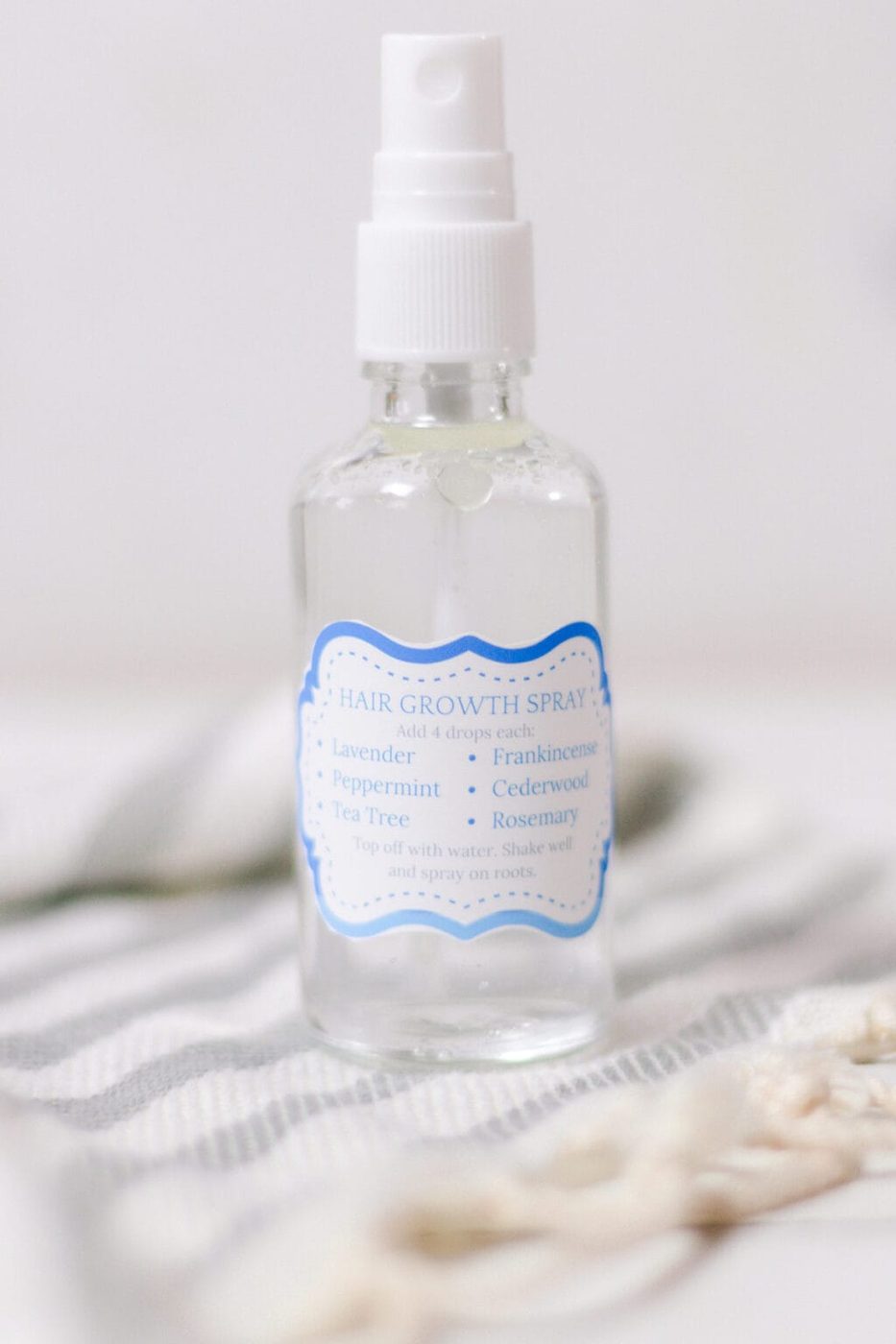 Hair growth spray with essential oils and water in the background.