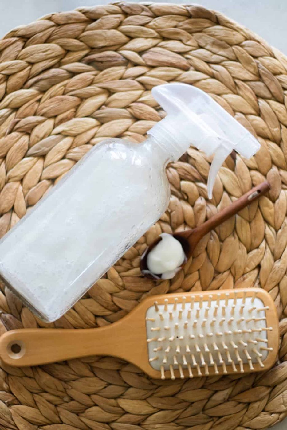 A spray bottle of hair heat protectant with a hair brush on a wicker placemat.