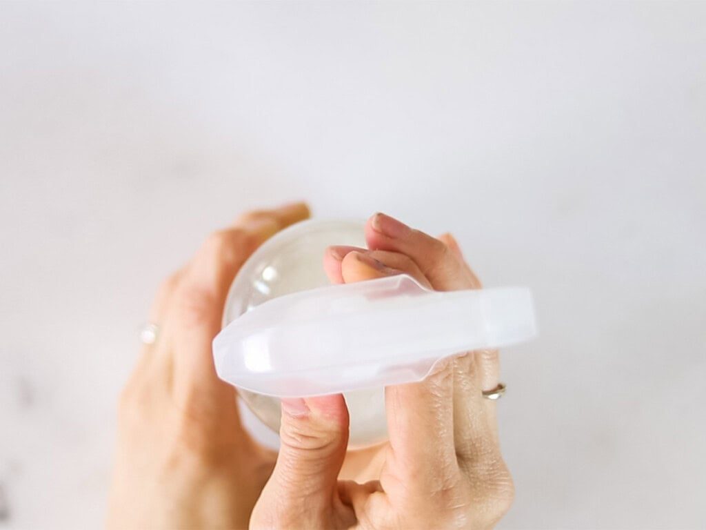 Tightening a lid on a spray bottle of hair heat protectant.