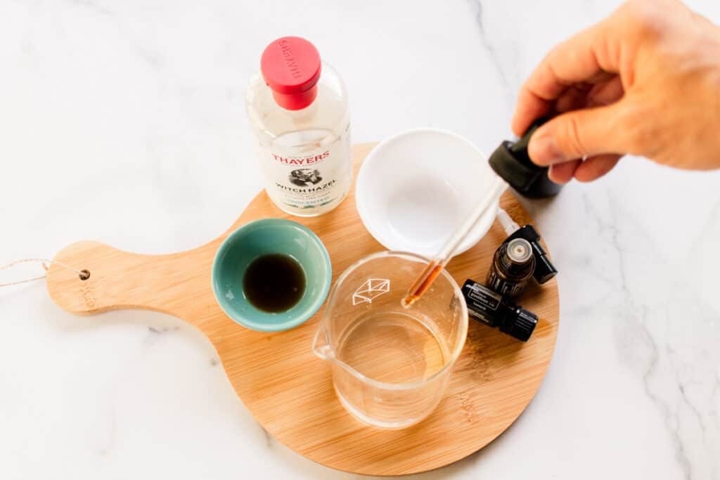 Using a dropper to add the vanilla extract to the perfume.