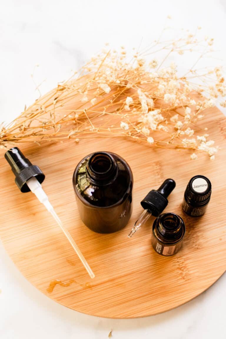 DIY hair perfume in a glass spray bottle on a white marble table.