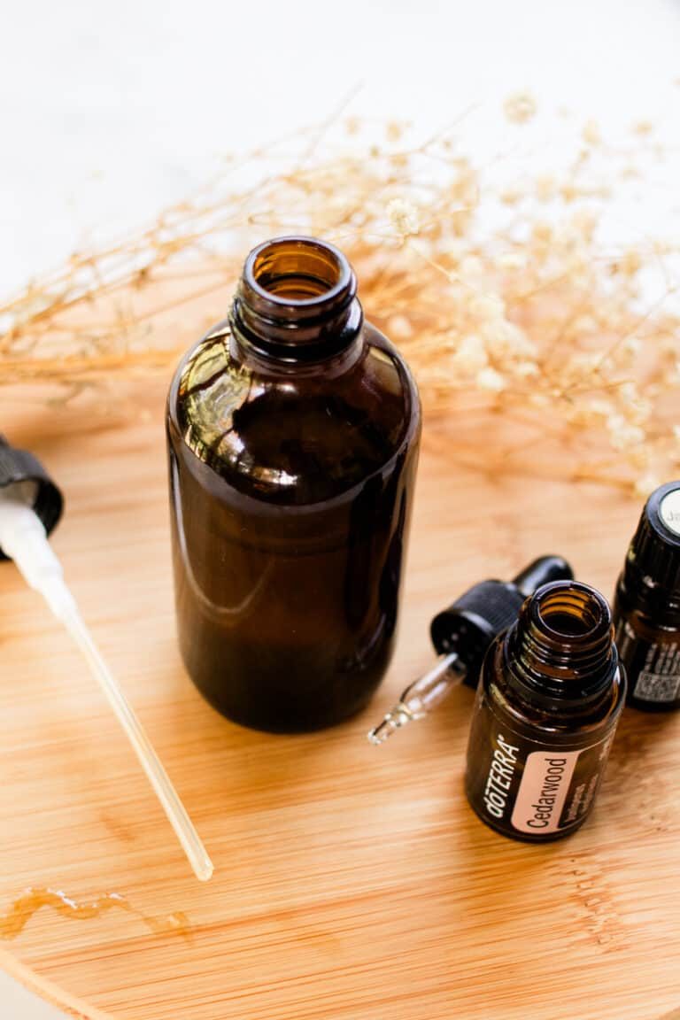 Hair perfume spray with fragrant oils next to it on a wooden board.