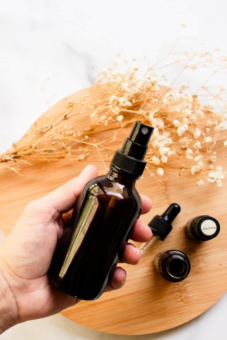 DIY hair perfume being shaken up in a dark colored spray bottle.