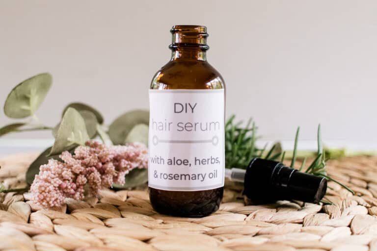 Homemade hair serum for hair growth with aloe vera surrounded by dried flowers and herbs.