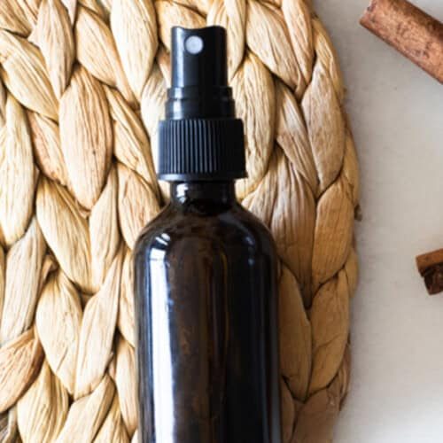 An amber bottle of hand sanitizer spray on a wicker placemat.