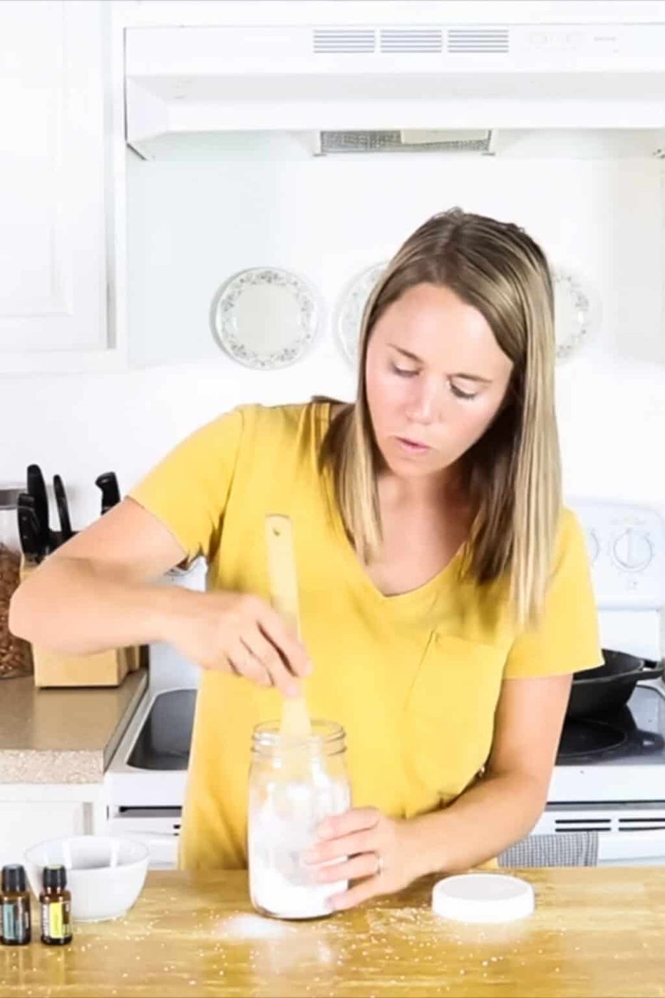 Stirring the ingredients for homemade scent boosters in a jar using a wooden spoon.