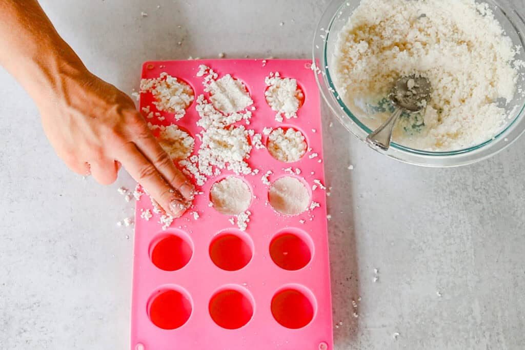 Pressing the soap pod mixture into cylindrical silicone molds.