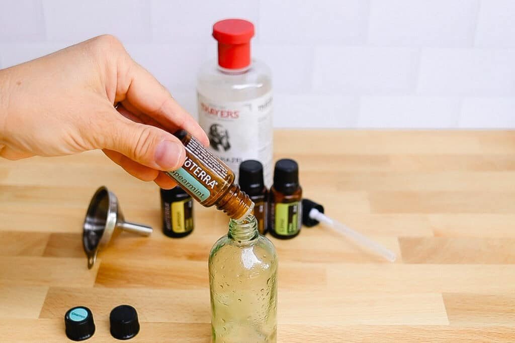Adding essential oils to glass spray bottle.