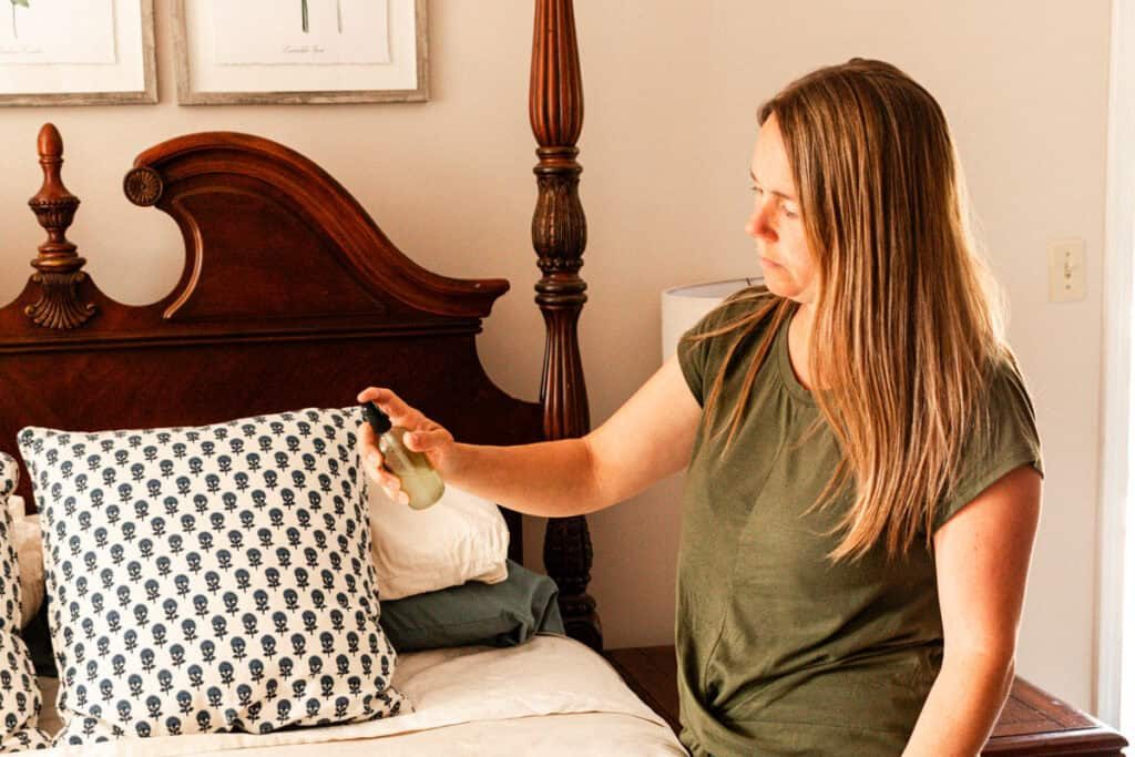 Spraying the DIY linen spray onto a bed.