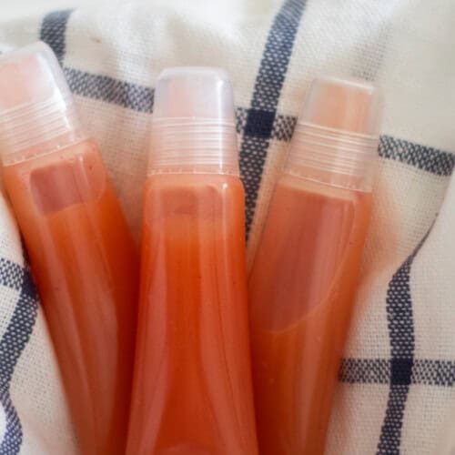 Three tubes of DIY lip gloss on a white and blue towel.