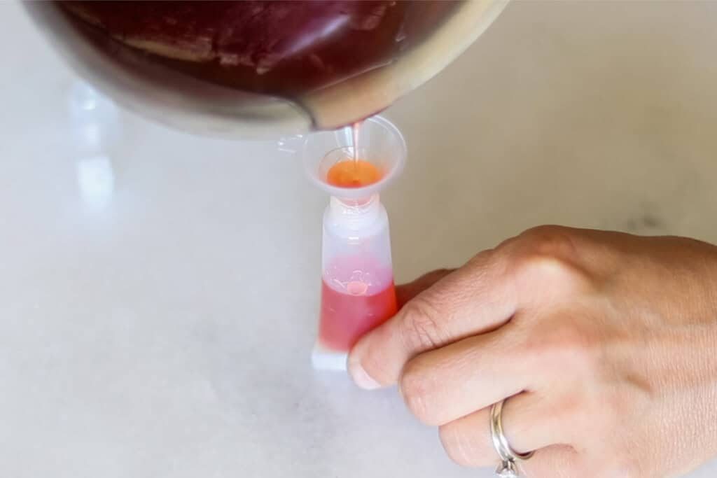 Pouring lip gloss into a squeeze tube.