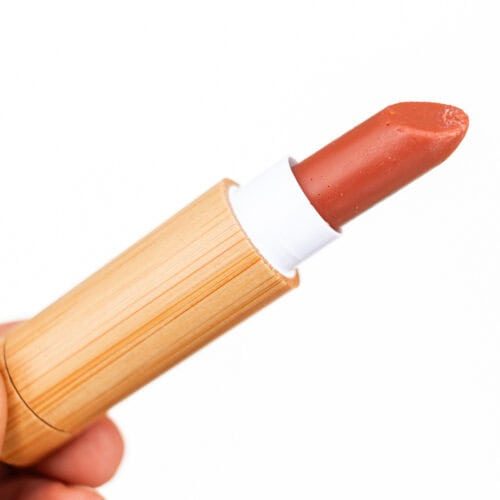 Holding a tube of homemade lipstick with a white background.