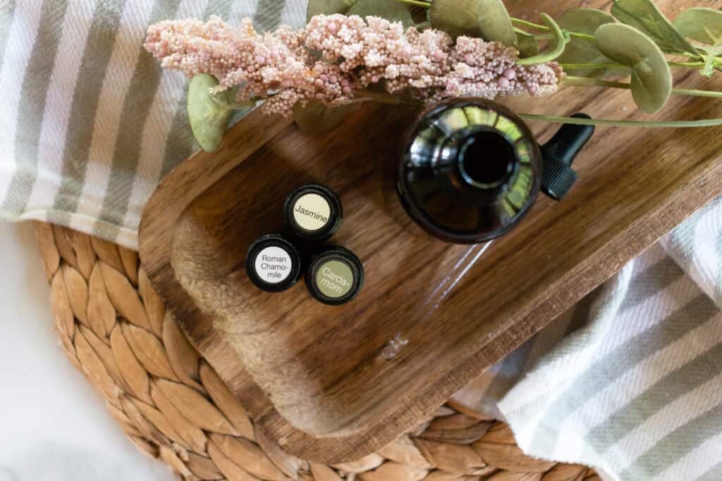 Essential oils x 3 and a bottle of DIY massage oil on a wooden board.