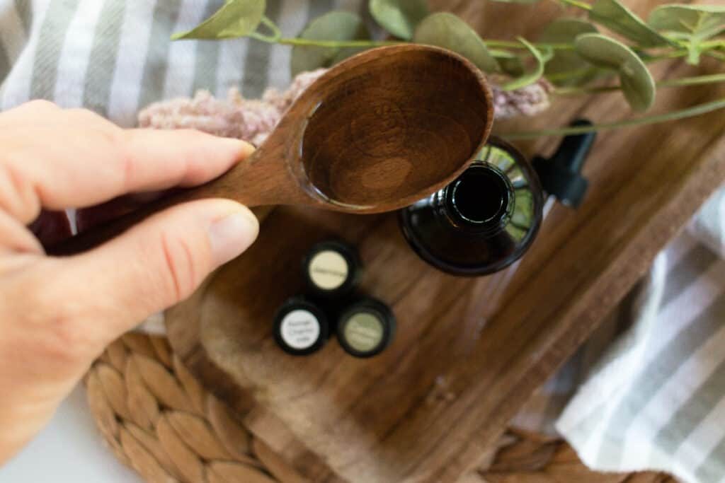 Adding oils to a dropper bottle using a wooden spoon.
