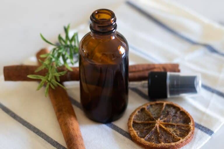 homemade men's cologne in amber color spray bottle with decorative dried spices.