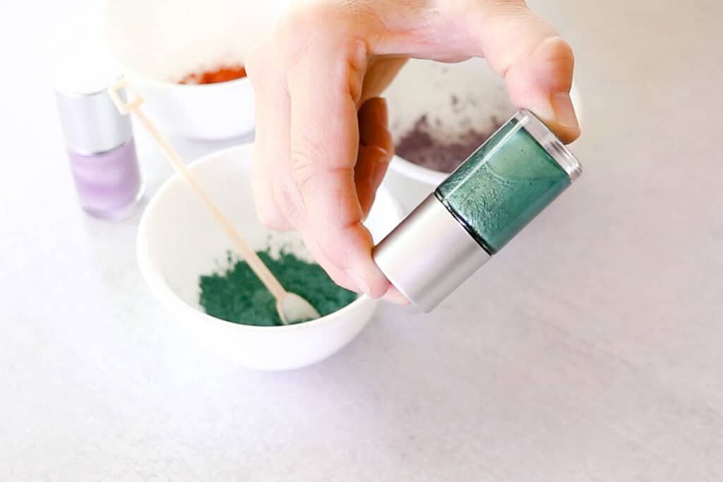 Shaking the bottle of nail polish to disperse the mica into the suspension base.