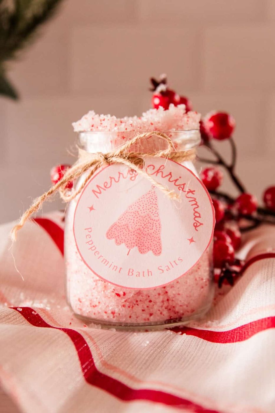 A jar of peppermint bath salts with a homemade label and red berries.