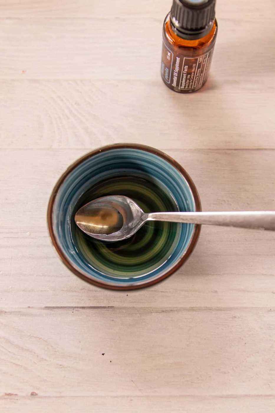 A bowl with jojoba oil and essential oils with a spoon sticking out of it.