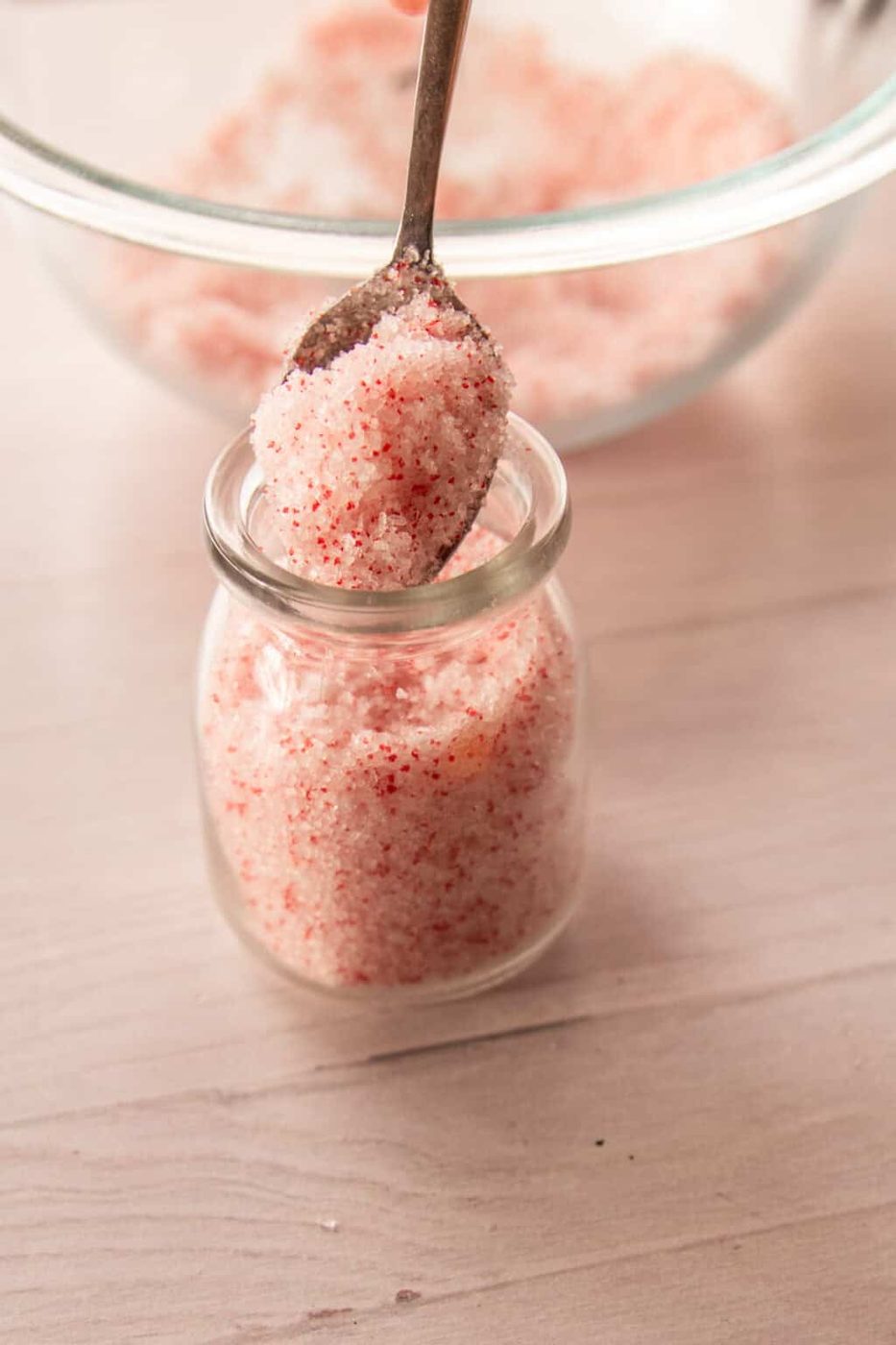 Pouring peppermint bath salts into a glass jar.