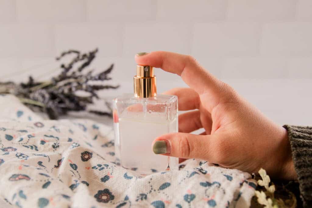 A hand holding a bottle of homemade perfume on a floral towel.