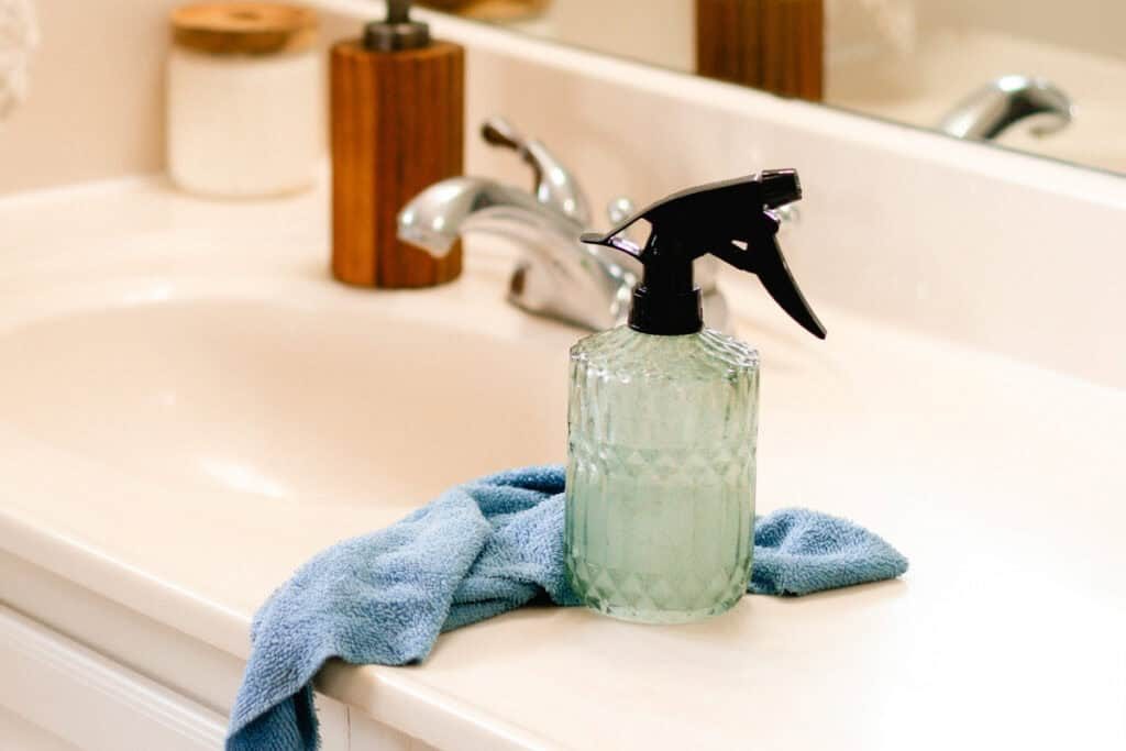 Soap scum spray sitting on a bathroom vanity with a microfiber cloth.