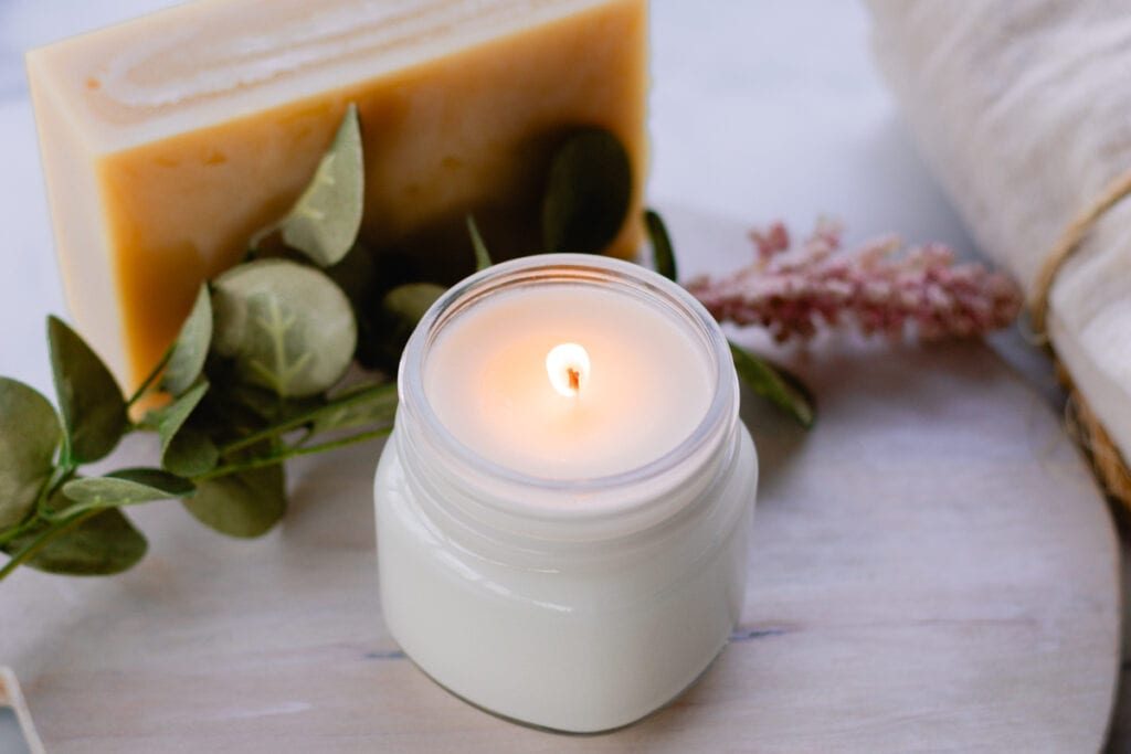 A lit soy candle in a glass jar.