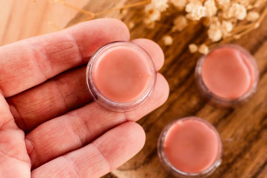 Holding a jar of tinted lip balm.