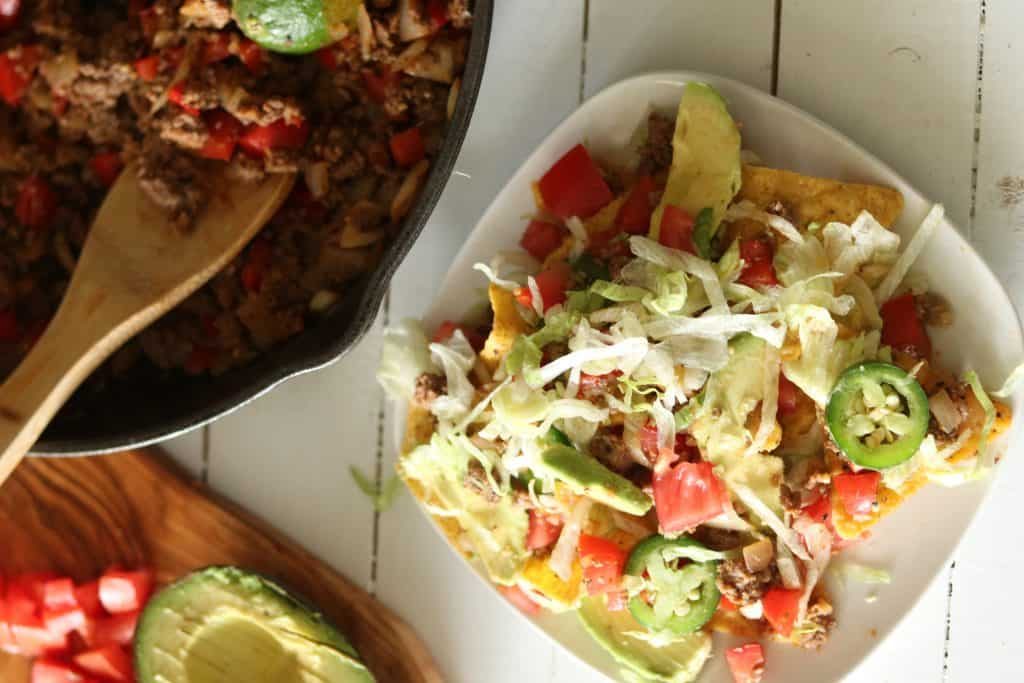 Homemade nachos topped with jalapeños, tomatoes, and avocado.