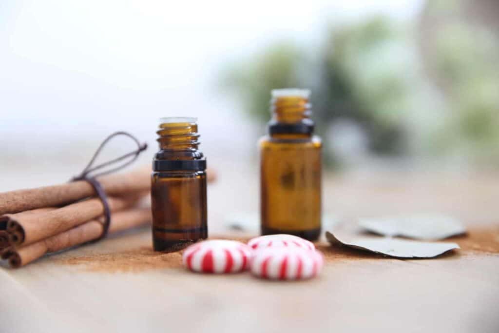 amber essential oil bottles on wood table with cinnamon sticks and eucalyptus leaves.