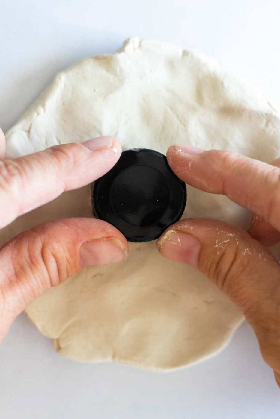 Pressing a circular cap into a sheet of clay.