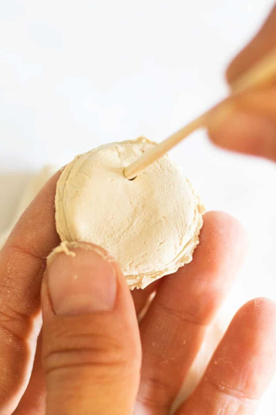 Poking a hole in a clay circle with a bamboo skewer.
