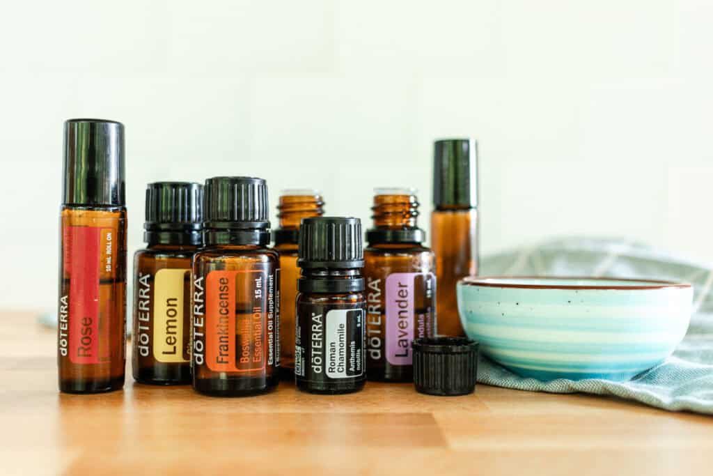 Essential oils, roller bottle, and carrier oil assembled on a wooden table.