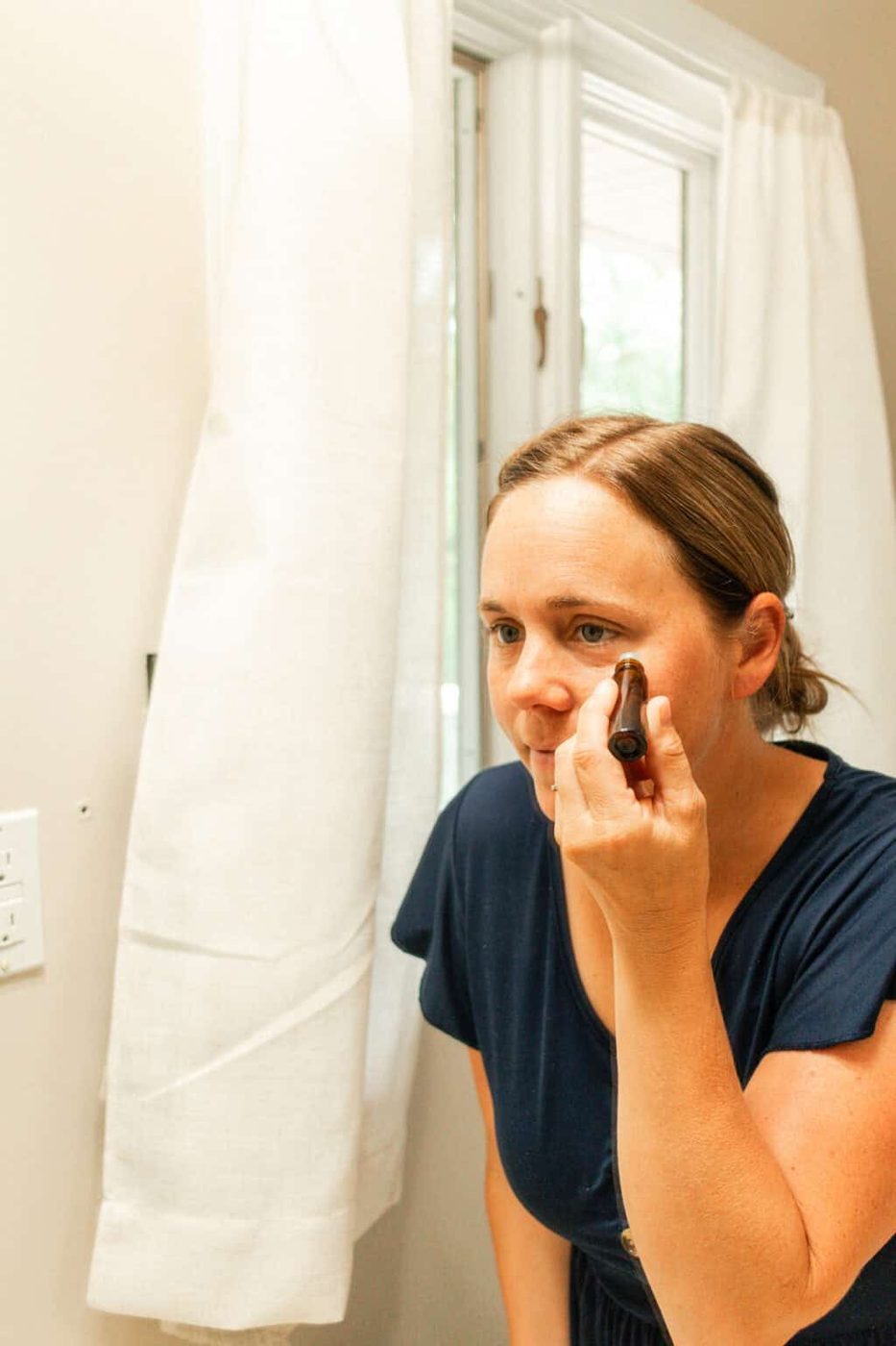 Applying an essential oil roller bottle under the eyes.
