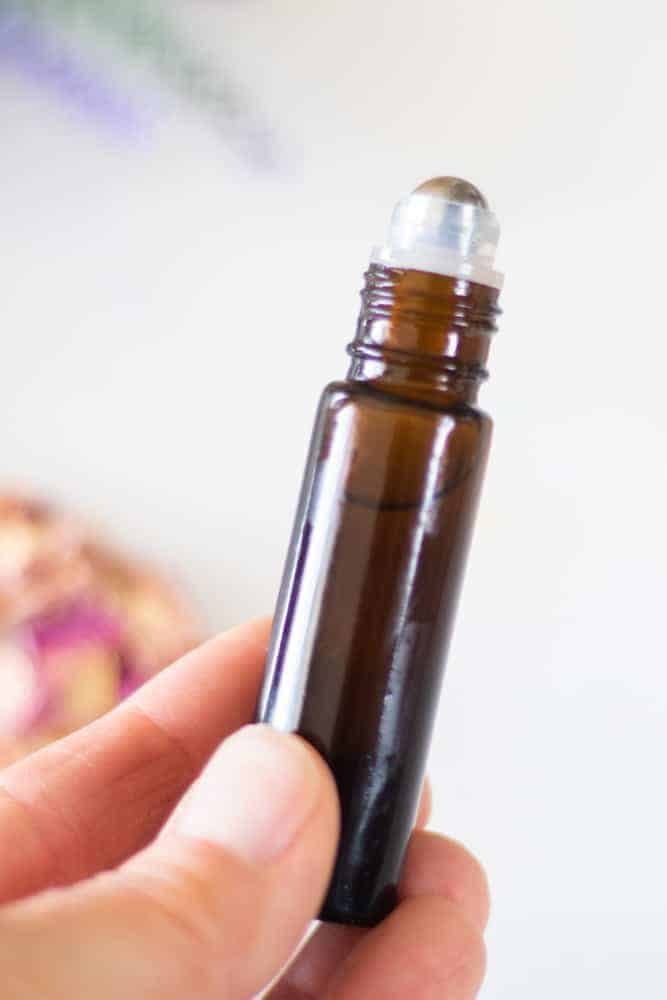 hand holding 10mL amber essential oil roller bottle