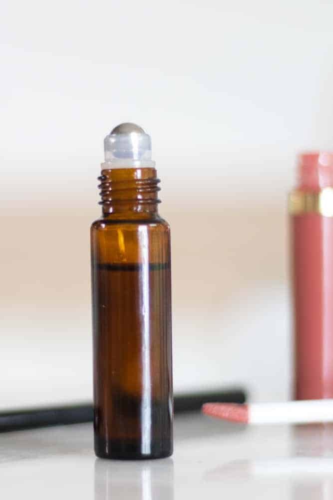 Amber color essential oil roller bottle with eyebrow growth serum with white background.
