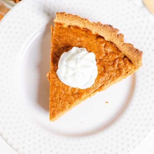 A slice of pumpkin pie with whipped cream on top.