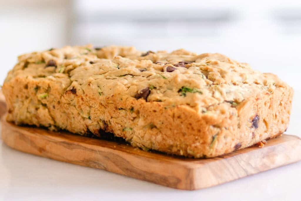 A loaf of gluten-free zucchini bread on a wooden board.